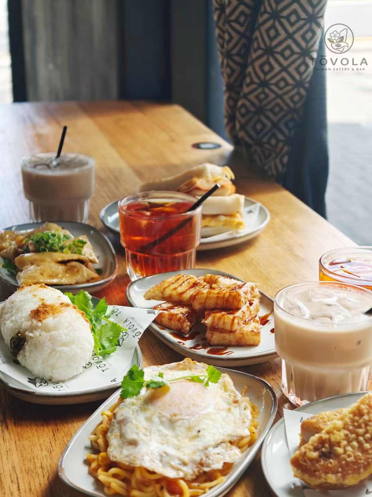 A table filled with Tôvola Taiwanese breakfast dishes and drinks